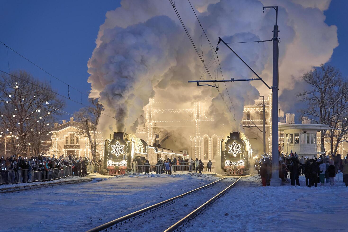 Russia, Peterhof, 07 January 2024. Two Santa Claus Trains leave the magically decorated building of the New Peterhof station, huge steam clubs, many people, incredible lighting photo