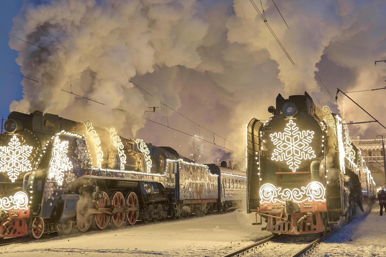 Russia, Peterhof, 07 January 2024. Two Santa Claus Trains leave the magically decorated building of the New Peterhof station, huge steam clubs, many people, incredible lighting photo