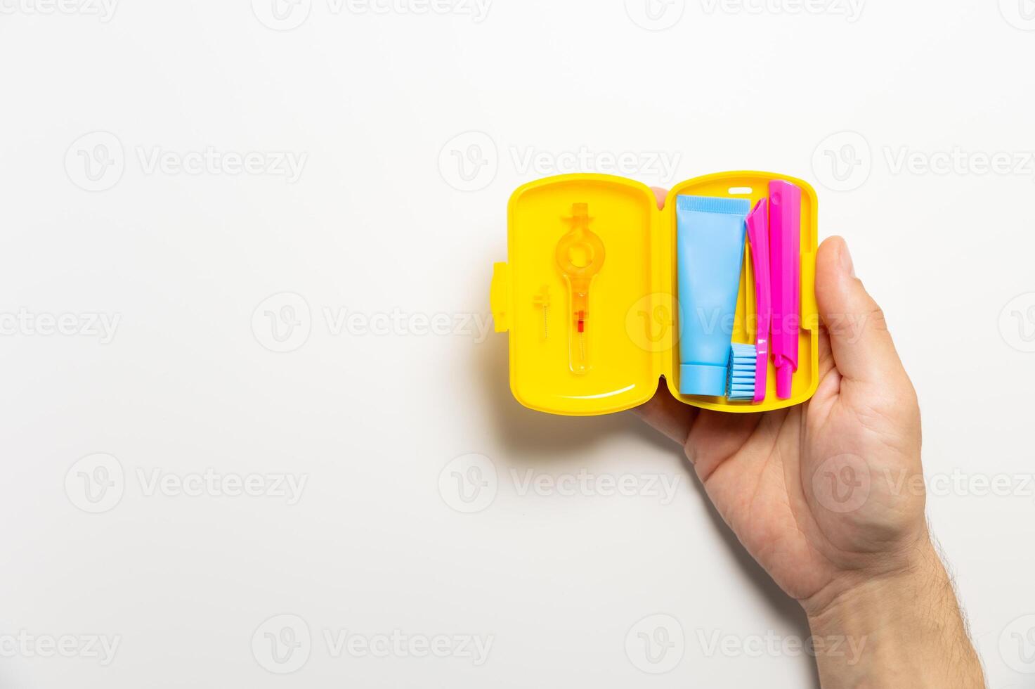 Dental hygiene and oral care products in a yellow travel cosmetic bag on a white background with copy space in a man's hand. Flat lay, top view composition photo