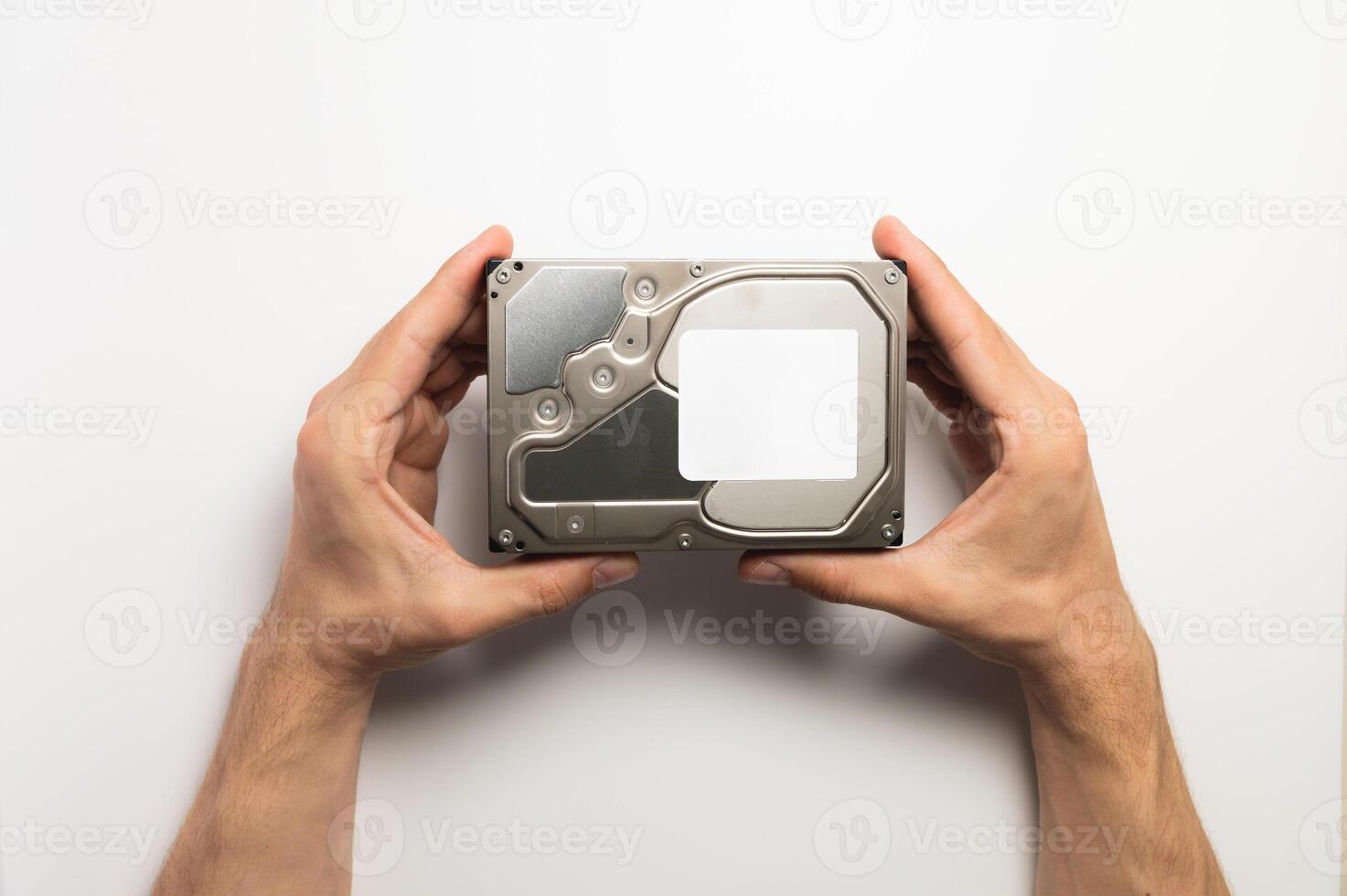 Man's hands showing a hard drive from a desktop computer close-up on a white background photo