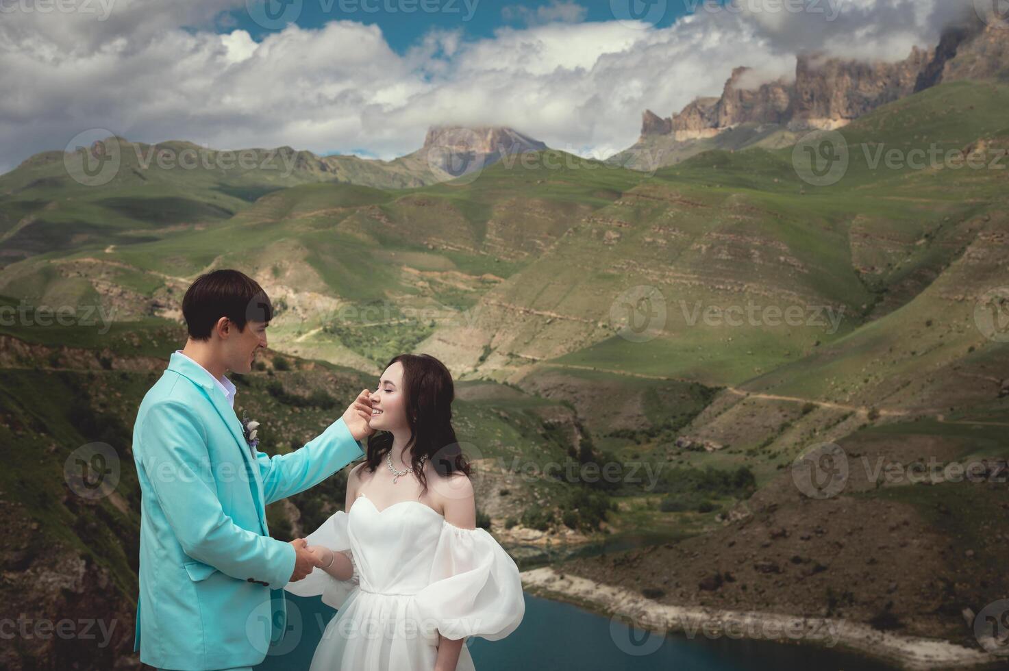 A young man and his wife stand in an embrace high in the mountains against the backdrop of epic rocks on a sunny day. Newlyweds wedding couple in the mountains photo
