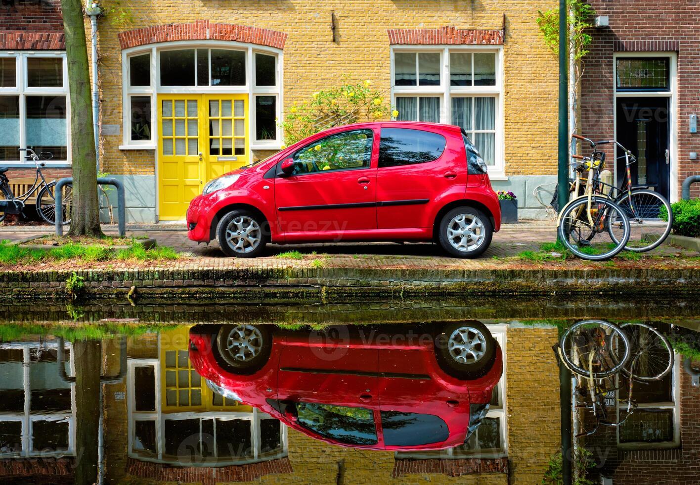 Red car on canal embankment in street of Delft. Delft, Netherlands photo