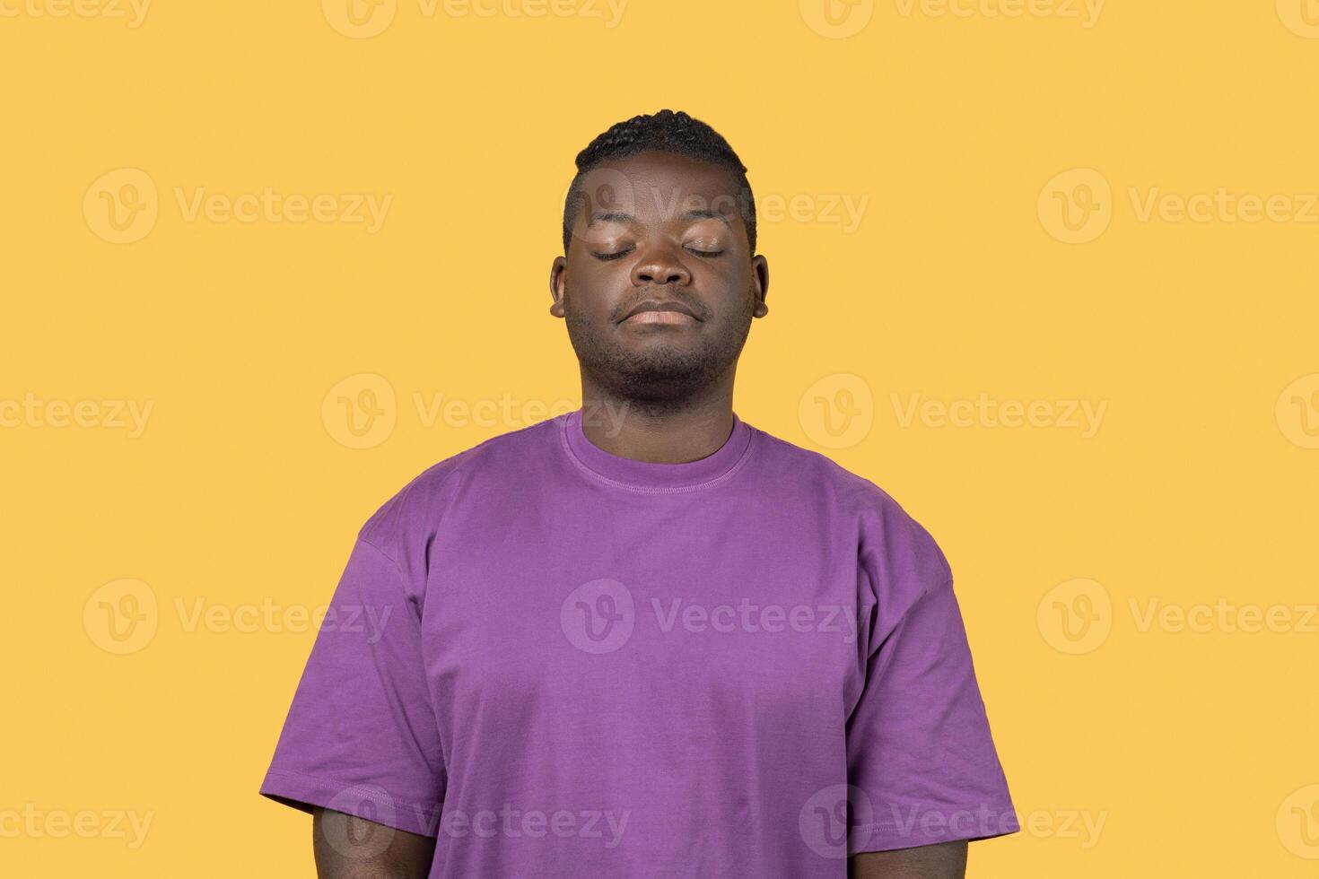 Tired Black guy posing sleepy with eyes closed over yellow background, expressing his exhaustion and lack of enthusiasm, wearing purple t-shirt. Studio portrait shot, negative emotions, insomnia photo