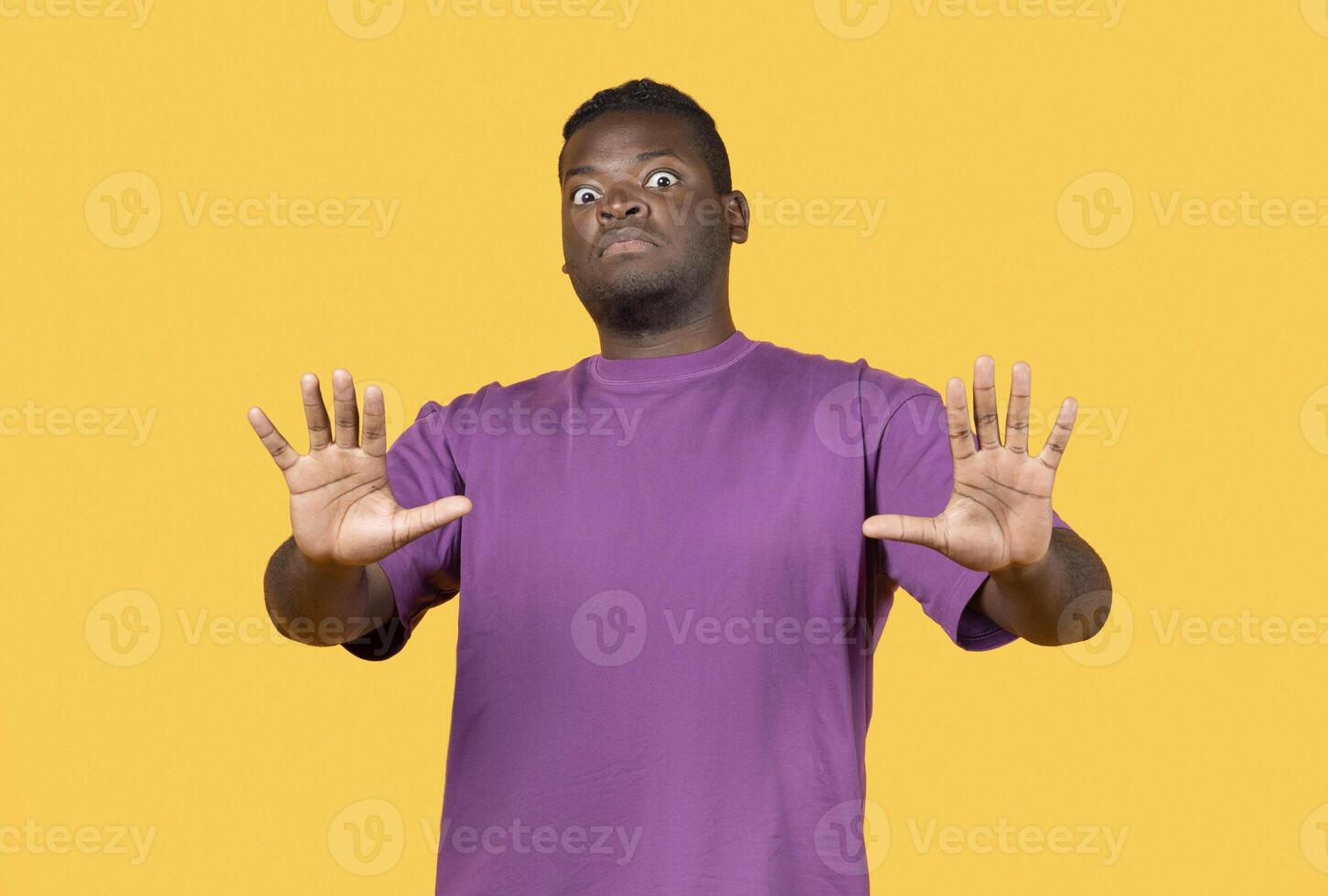 Shocked young african american man making stop gesture with hands, pushing camera back standing over yellow background in studio. Disgust, say no and negative emotion, sign of personal space photo