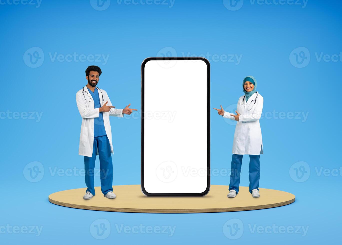 Telemedicine, virtual consultaion, ehealth. Cheerful middle eastern doctors in medical workwear pointing at huge phone with white blank screen, isolated on blue background, mockup, collage photo