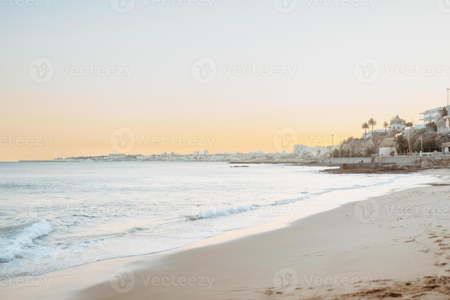 Summer landscape at beach at sunset, silky brown sand with waves rolling into the beach, hotels and houses in the background, banner, copy space photo