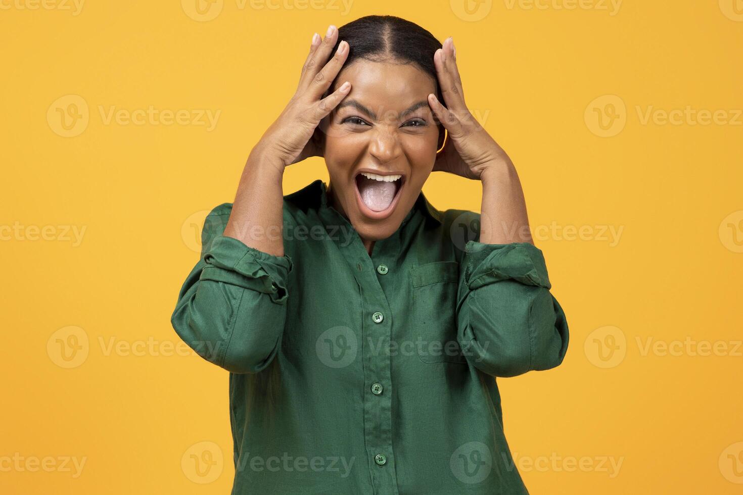 Wow Offer. Emotional Black Woman In Green Shirt Shouting Touching Head, Expressing Crazy Emotions Of Joy, Reacting To Amazing News, Posing Looking At Camera Standing On Yellow Studio Background photo