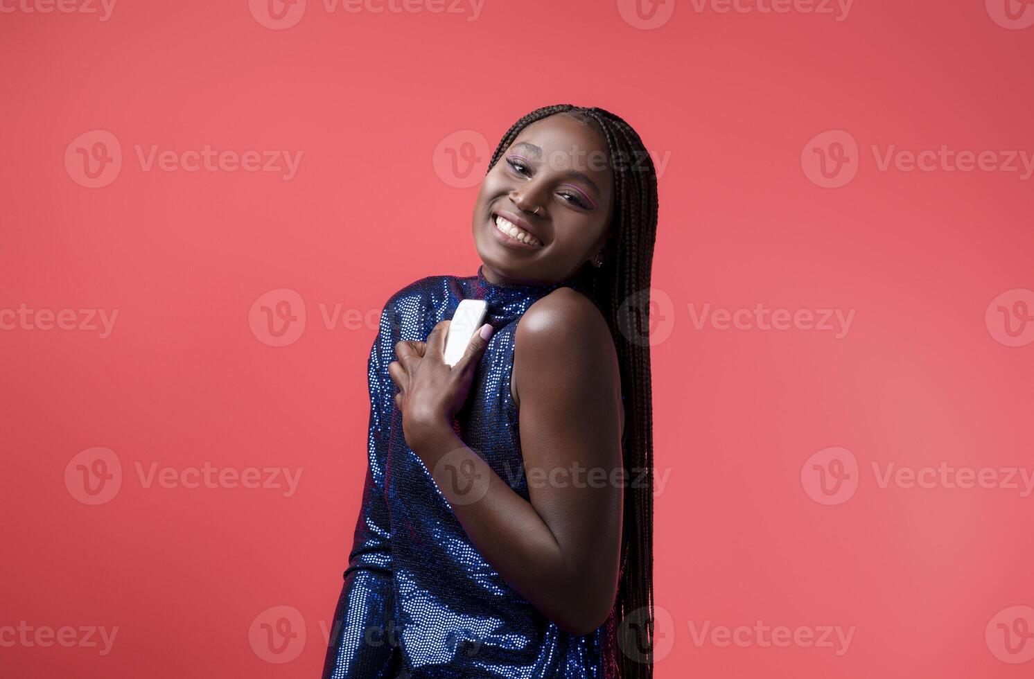 Stylish Young Black Woman In Sequin Dress Holding Smartphone And Looking At Camera, Happy Millennial African American Fashion Model Enjoying Mobile Communiation, Posing On Red Background, Copy Space photo