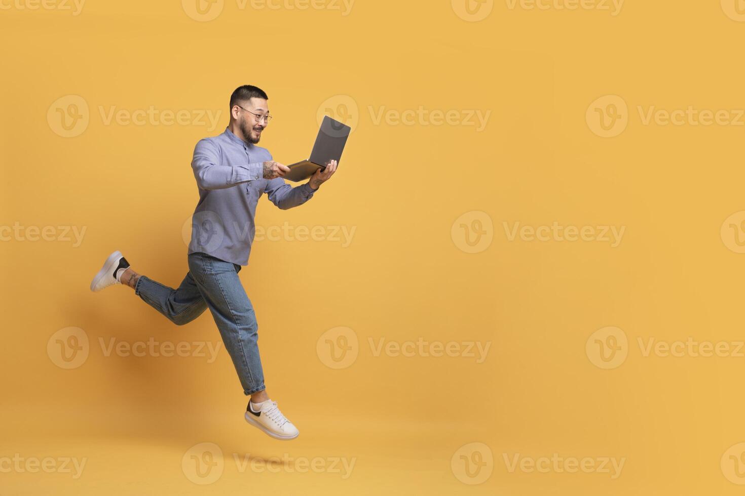 Online Sales. Excited Young Asian Man With Laptop Computer Running Over Yellow Background, Happy Millennial Male Looking At Screen And Smiling, Enjoying Website Offer, Full Length, Copy Space photo