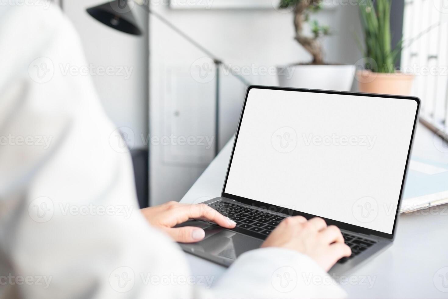 Unrecognizable businesswoman using laptop computer with white blank screen, typing on keyboard, mockup for ad, website design, copy space photo