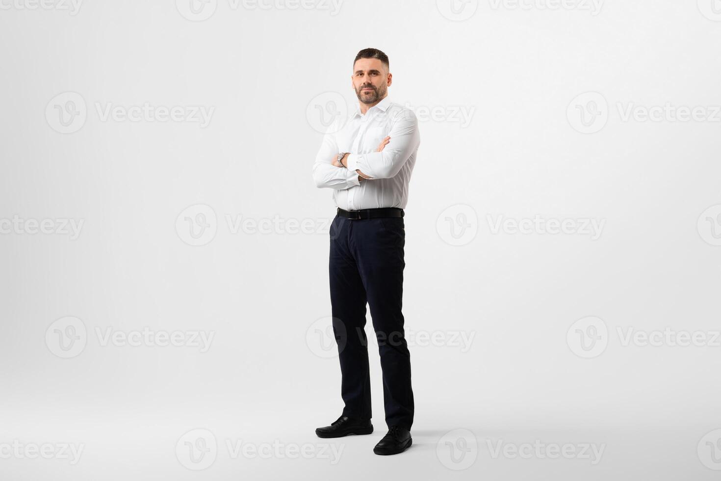 Full length portrait of confident middle aged businessman in shirt standing with folded arms, man entrepreneur posing on light studio background, copy space photo