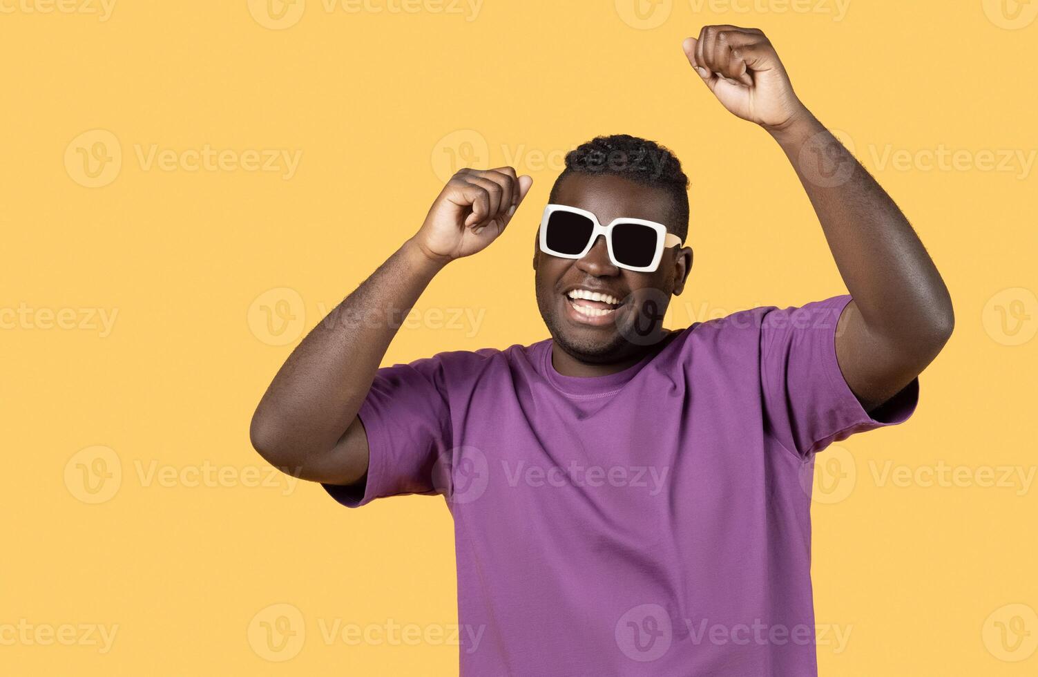 Positive Summer Vibes. Happy African American Man Wearing Sunglasses Shaking Fists Looking At Camera Posing On Yellow Background. Relaxed Guy Advertising Vacation Offer And Celebrating Good News photo