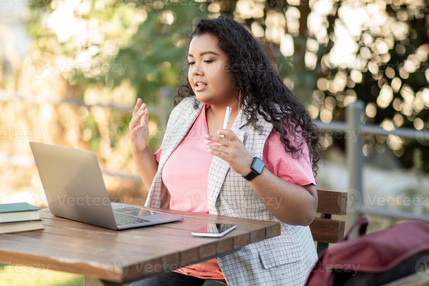 E-Learning. Latin Student Woman Studying Online Through Call On Laptop, Talking To Webcam During Virtual Lecture Sitting In Park Outside. College Education And Internet Technology photo