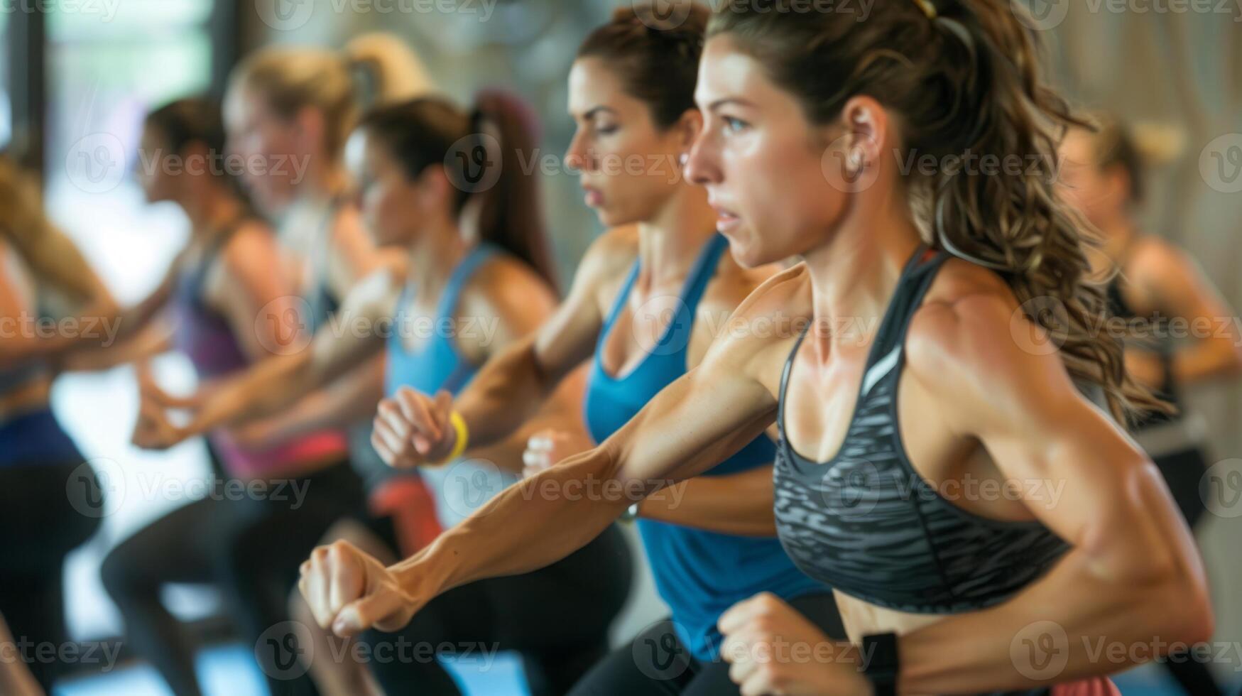 Women exercising in a group fitness class, with the focus on the woman in the foreground who is leading the class. photo