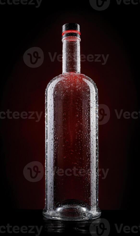 Empty wet glass bottle on a beautiful illuminated background. photo