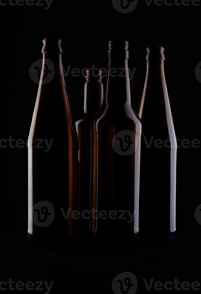 Several beer bottles on a dark background in backlight. photo