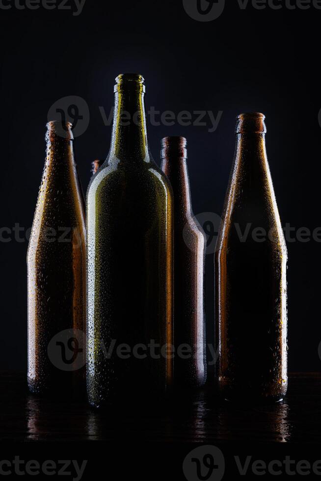 Several beer bottles on a dark background in backlight. photo