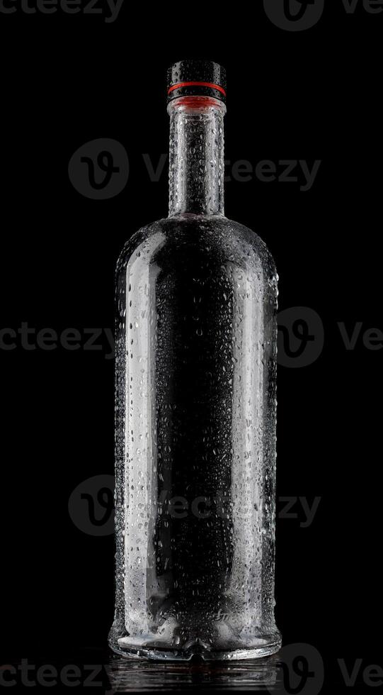 Empty wet glass bottle on a dark background. photo