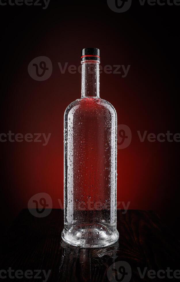 A wet bottle on a beautifully illuminated background. Smoke around a glass bottle. photo