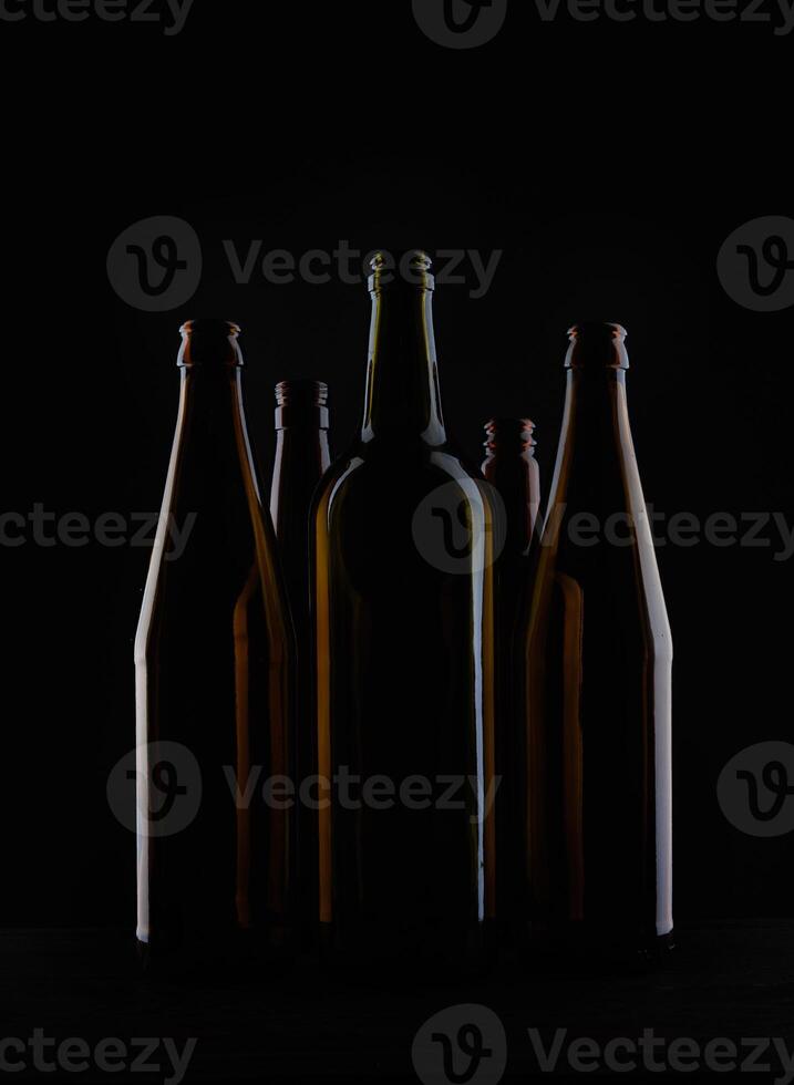Several beer bottles on a dark background in backlight. photo