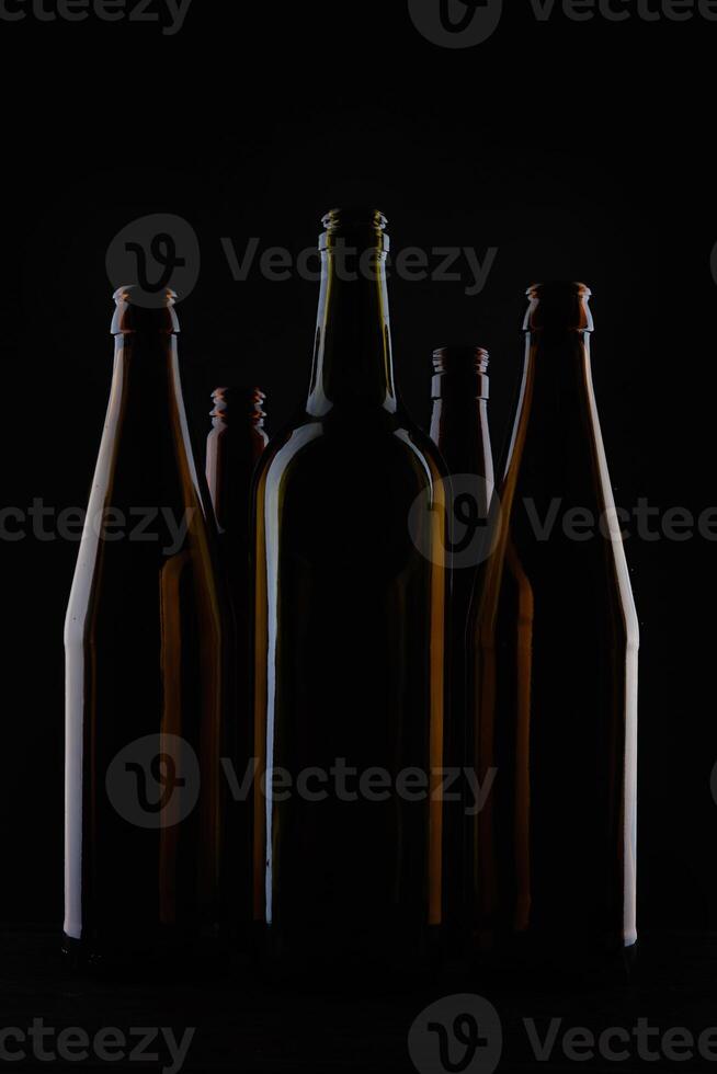 Several beer bottles on a dark background in backlight. photo