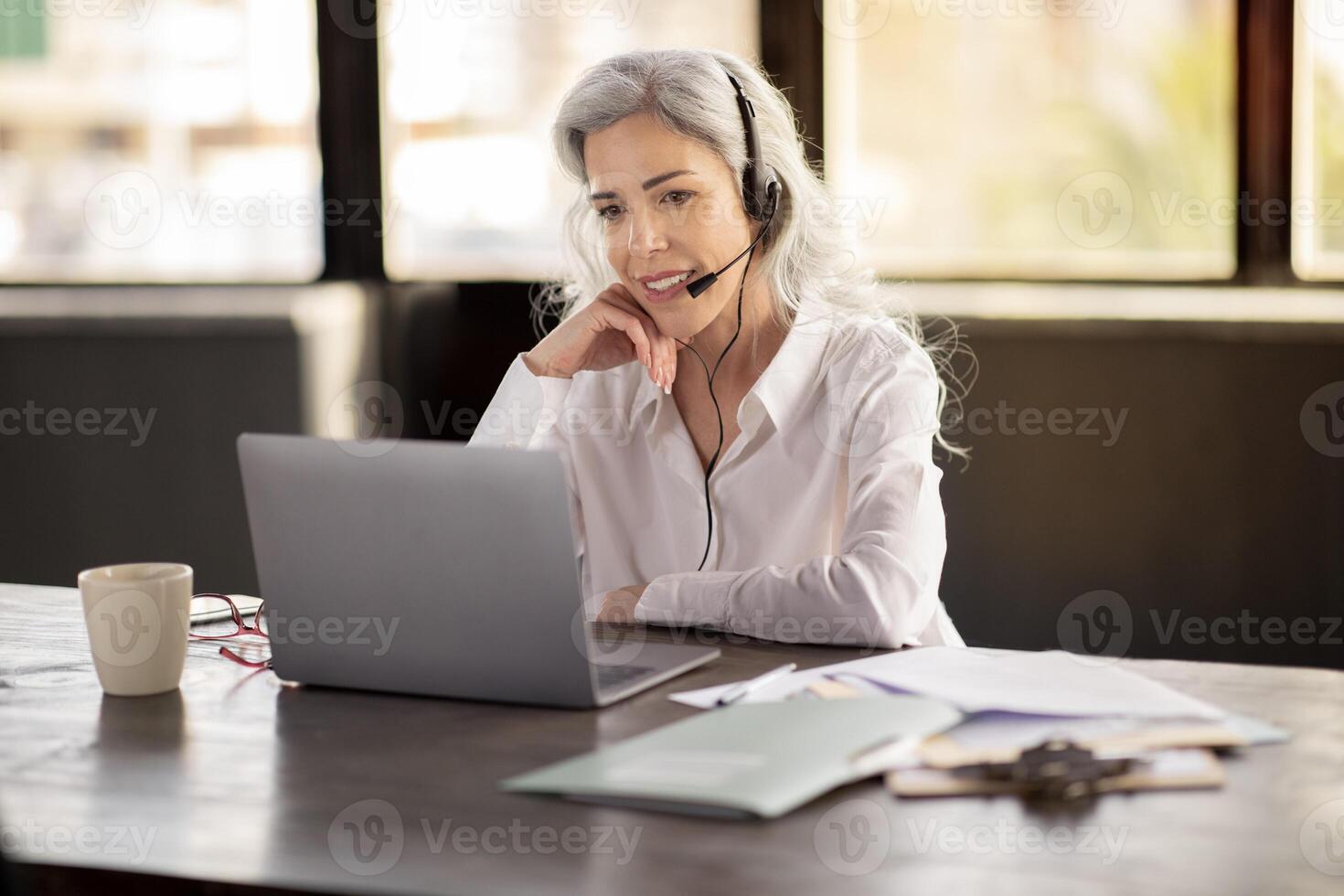 Professional Clients Support. Smiling Businesswoman At Laptop Wearing Headset, Calling Providing Assistance In Virtual Communication With Customers And Colleagues In Office Interior photo