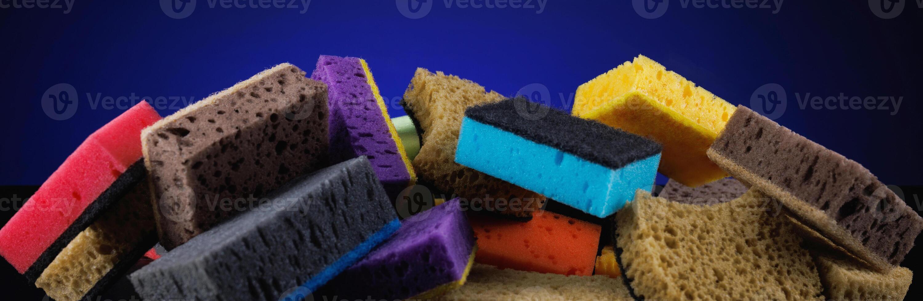 Background of mixed colorful sponges for washing dishes. Household cleaning sponge on a blue background. photo