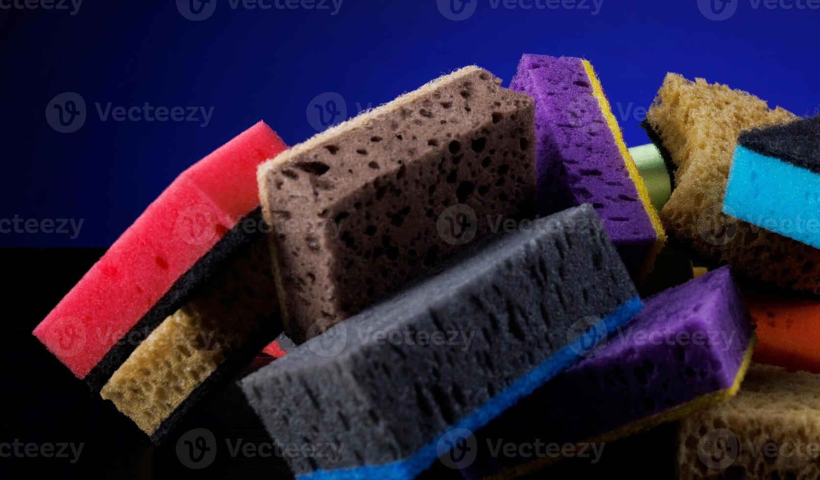 Background of mixed colorful sponges for washing dishes. Household cleaning sponge on a blue background. photo