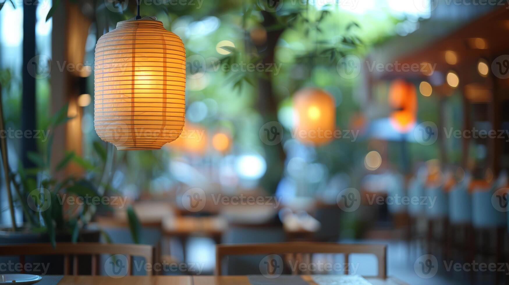 Lanterns create a warm glow in a cozy outdoor cafe setting at dusk, with blurred background foliage and seating. photo