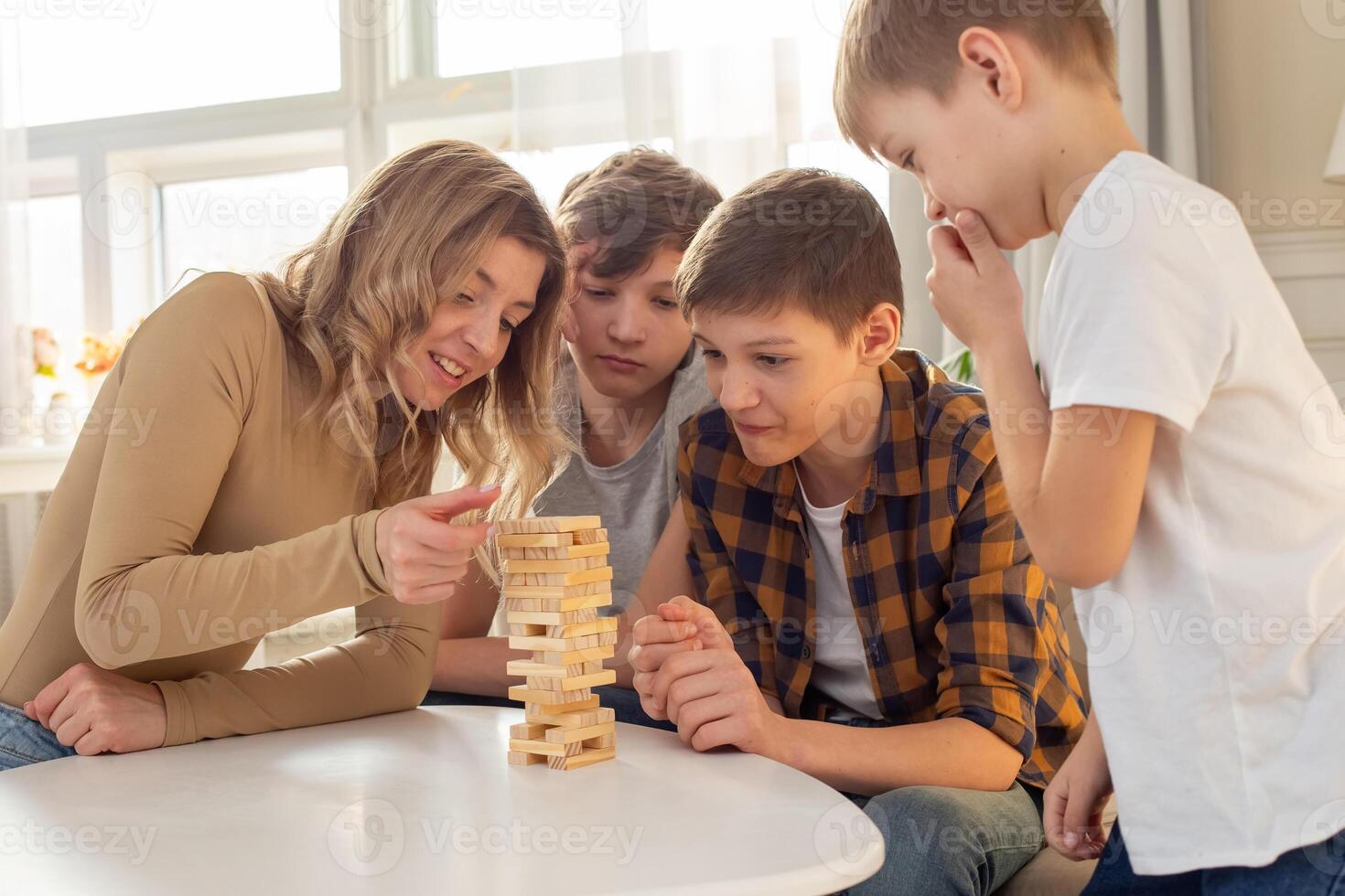 Happy family , in room play a board game made of wooden rectangular blocks photo