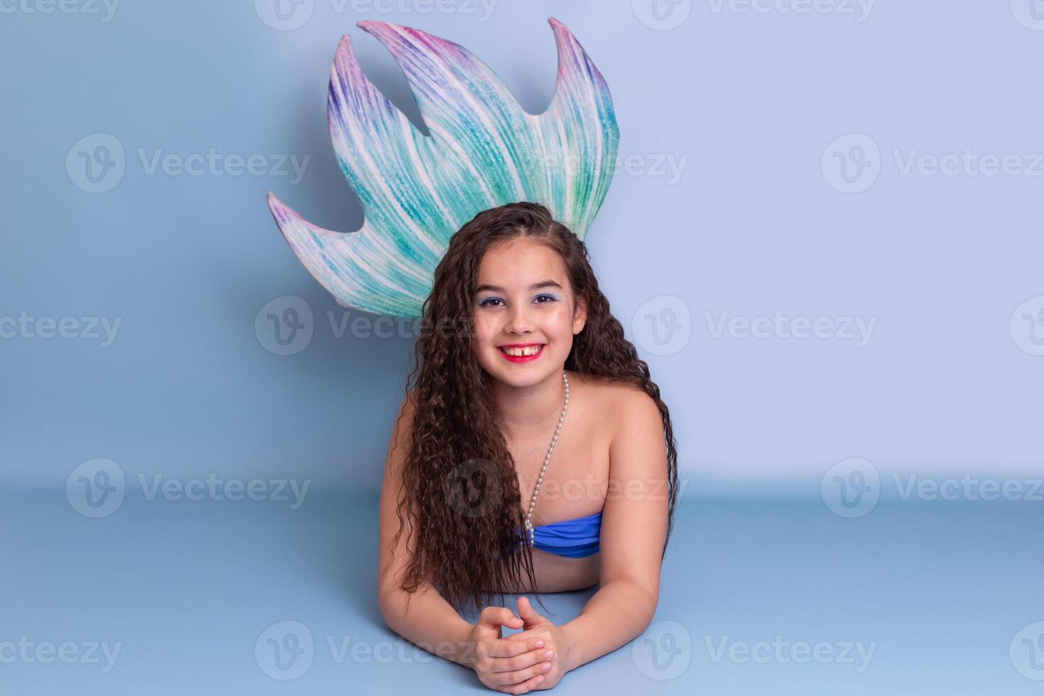 Beautiful girl in a mermaid costume lie on light-blue background photo