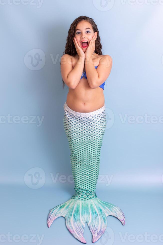 Pretty happy surprised girl in mermaid costume stand on blue background photo