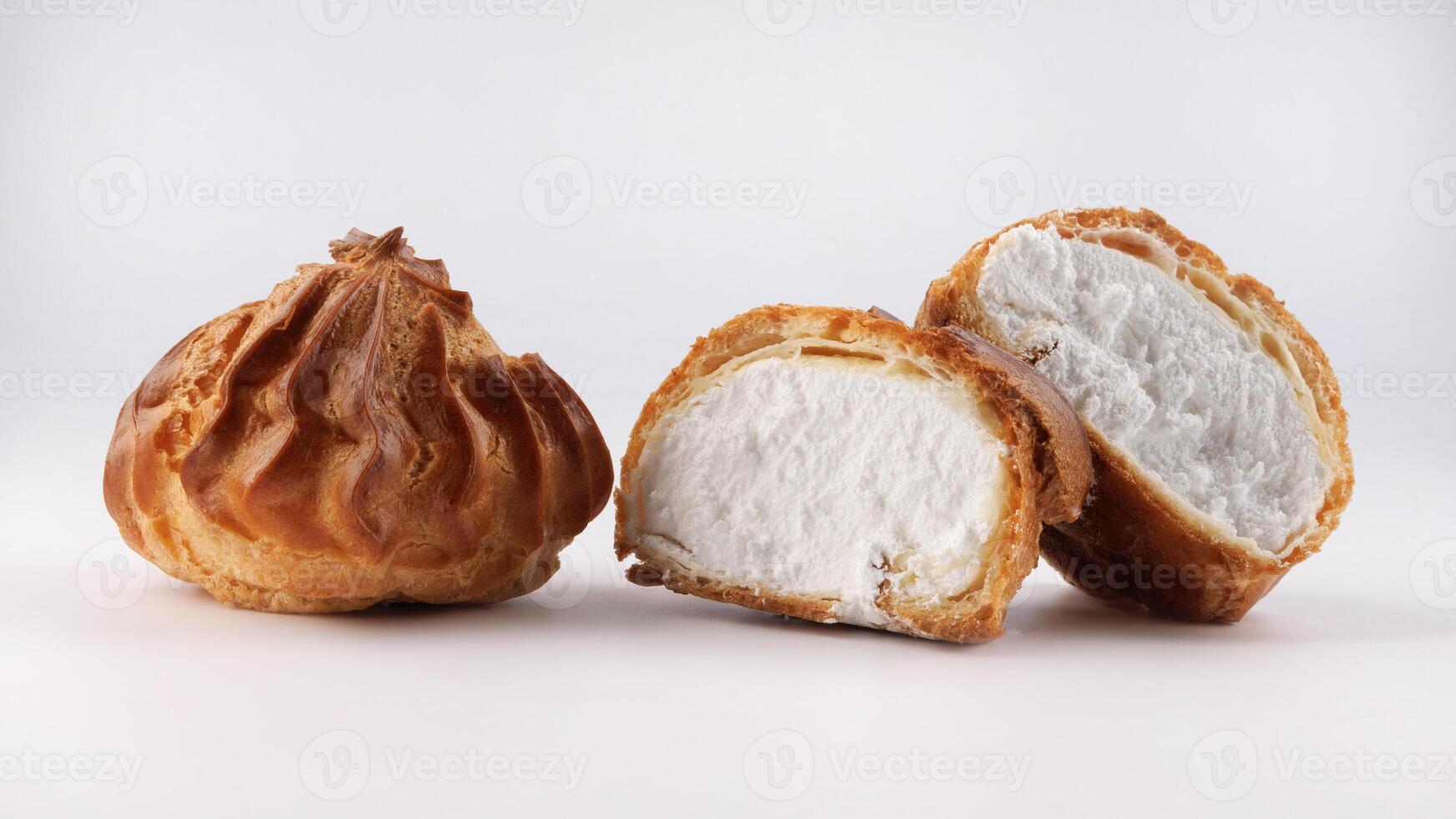 Cut in half and whole porophytole with white cream isolated on a white background. Eclair with cream. photo