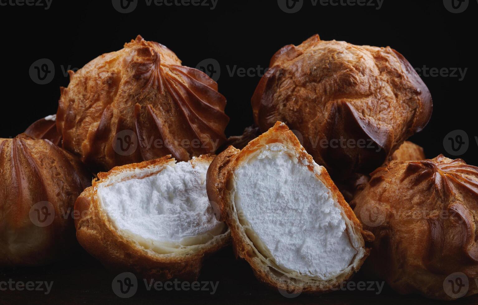 Profiteroles with white custard on a wooden board. Mini eclairs with white cream. photo