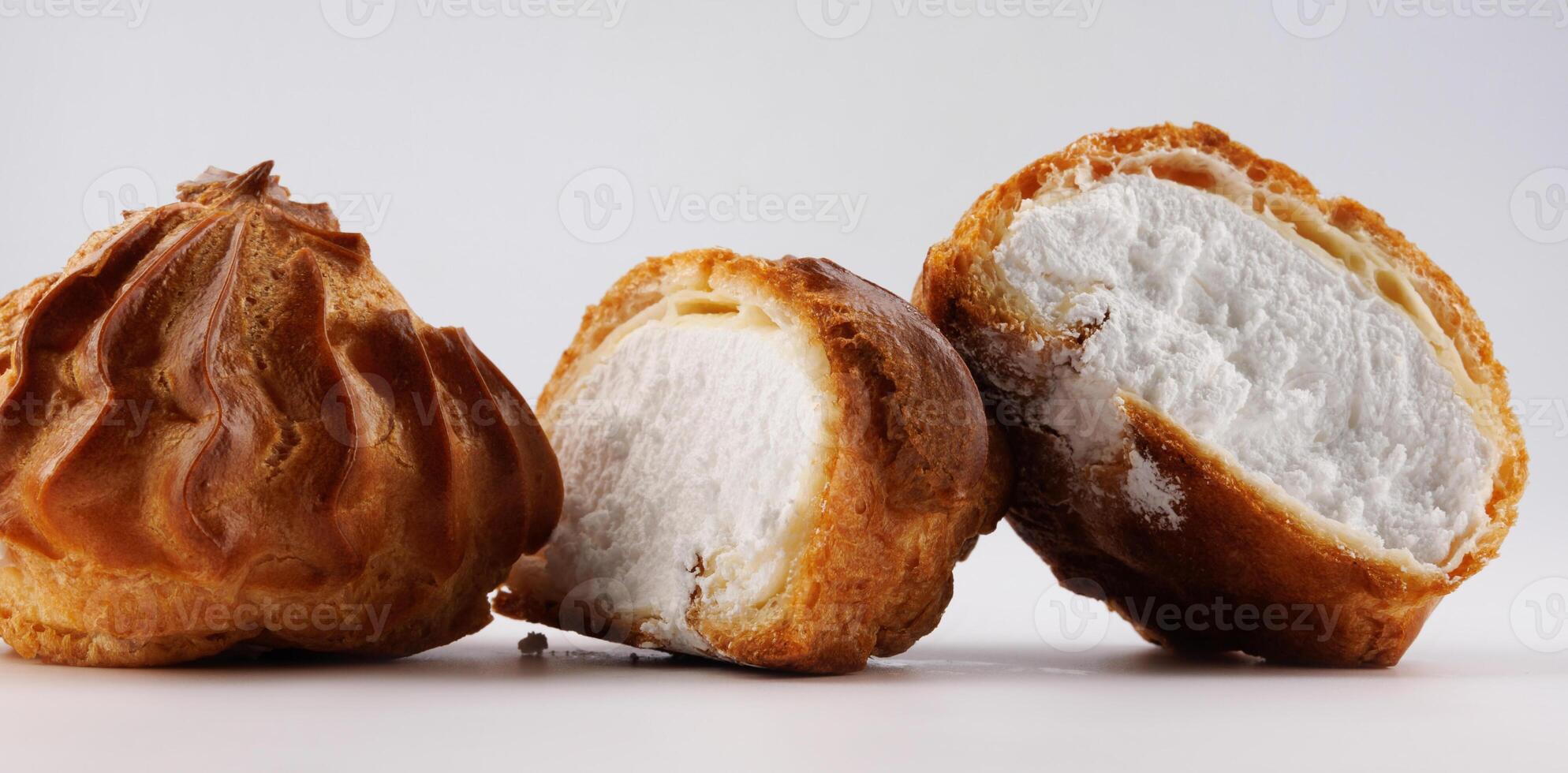 Cut in half and whole porophytole with white cream on a white background. Eclair with cream. photo