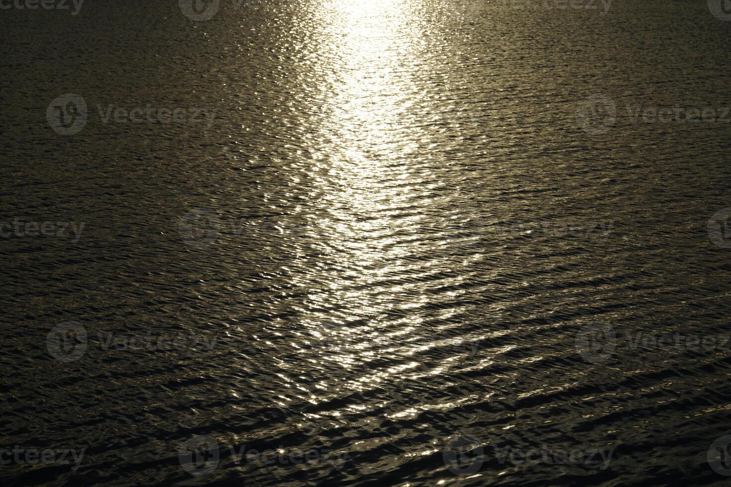 Sun reflecting in water surface at sunset photo