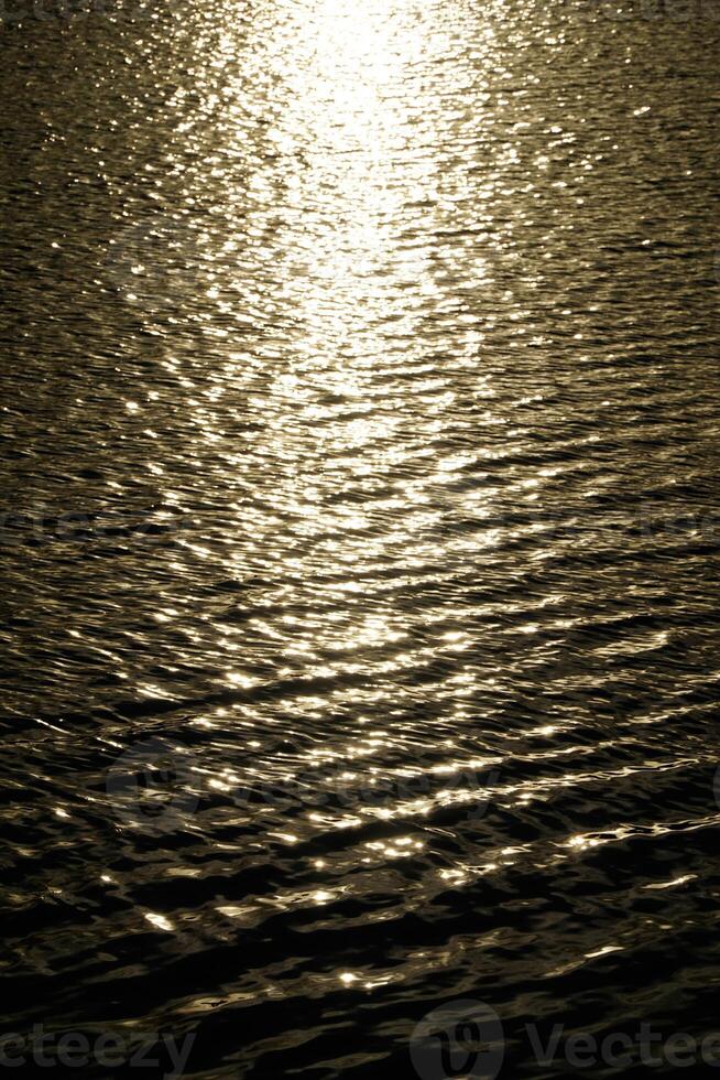 Sun reflecting in water surface at sunset photo