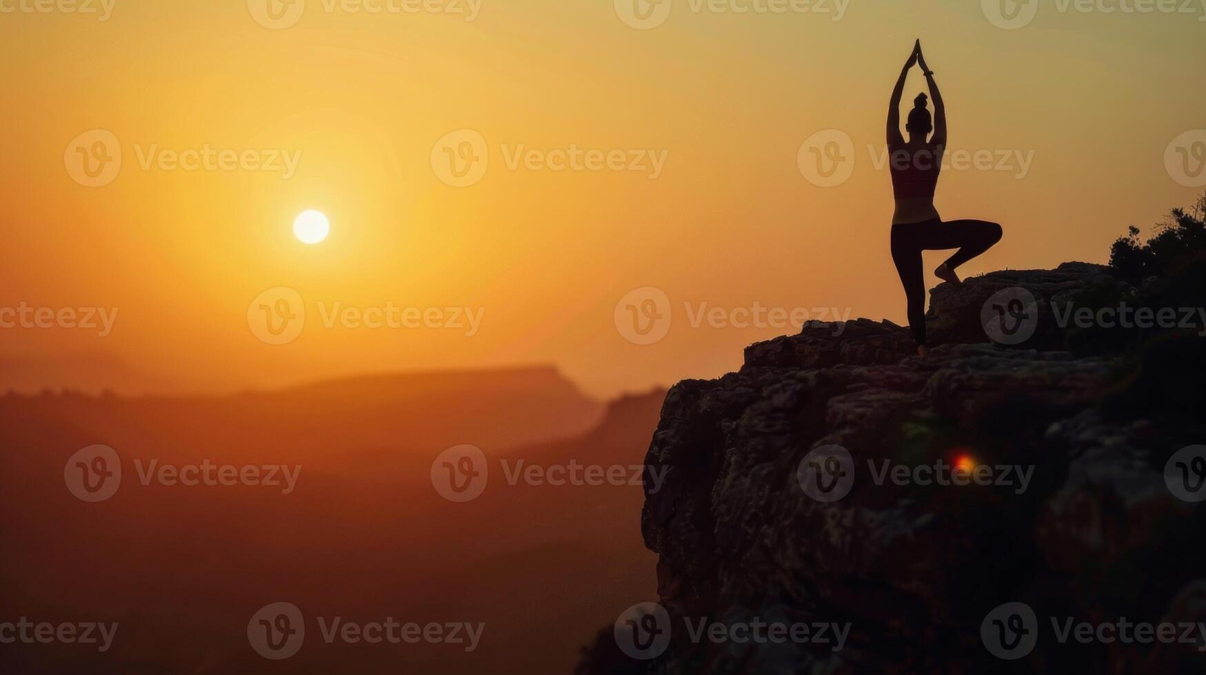 A silhouetted figure of a person practicing yoga poses on a cliff during sunset highlighting the brainboosting benefits of a regular yoga practice photo