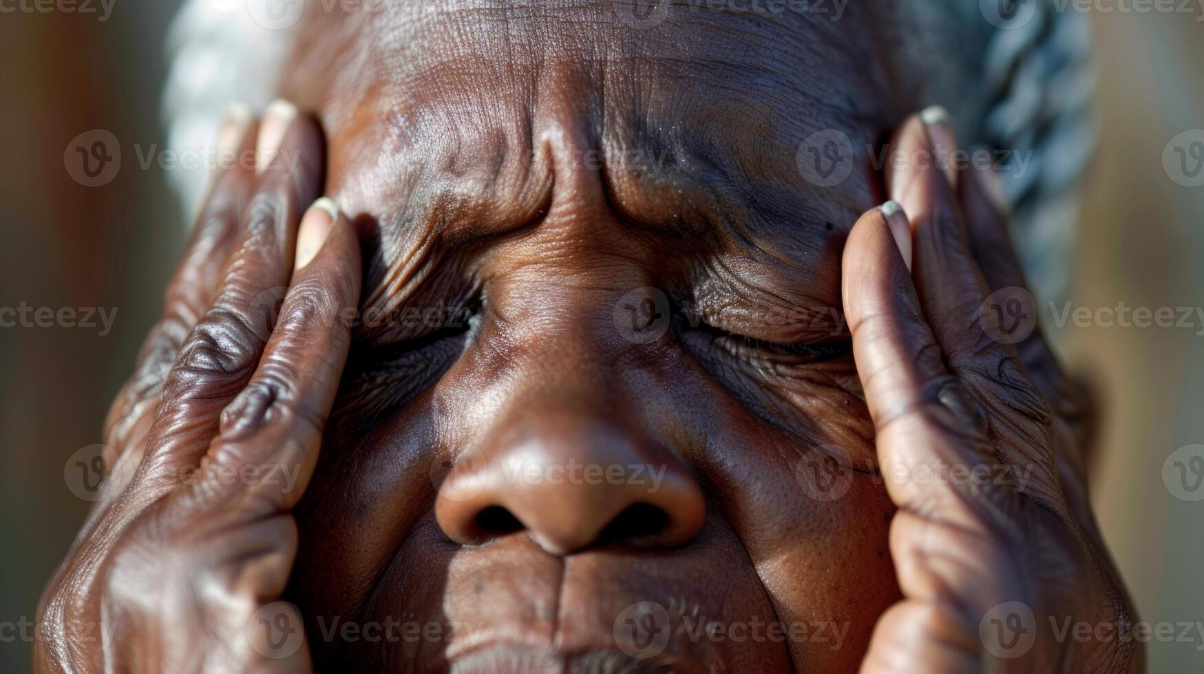 A closeup of an older persons face eyes closed and hands rubbing temples in frustration photo