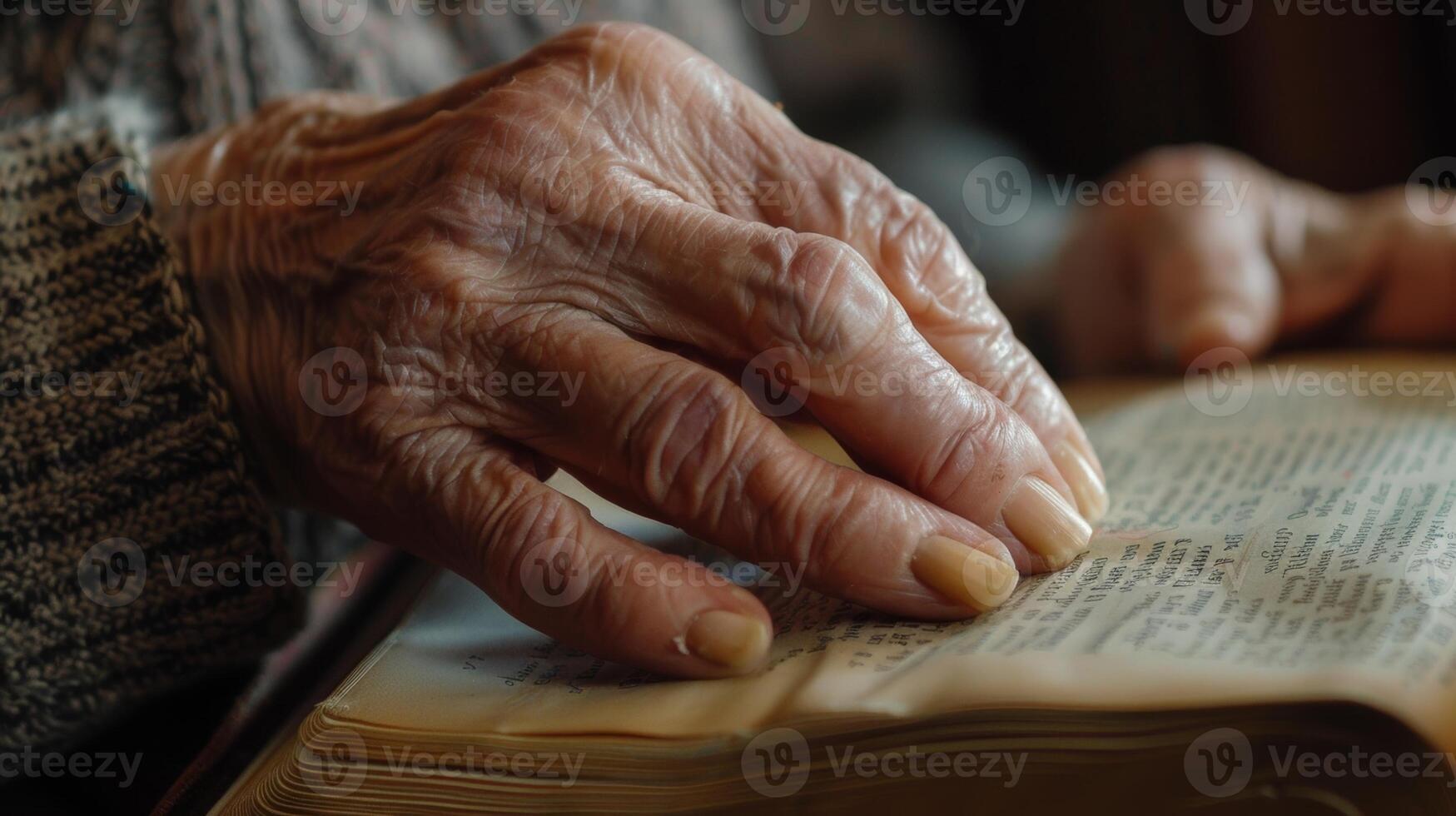 A closeup of an elderly persons hand trembling as they try to turn the pages of a book photo