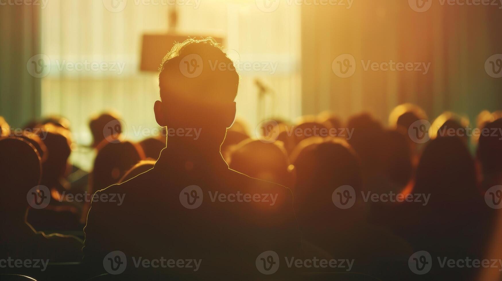 Faint silhouettes of a speaker and a defocused audience at a wellattended public lecture photo