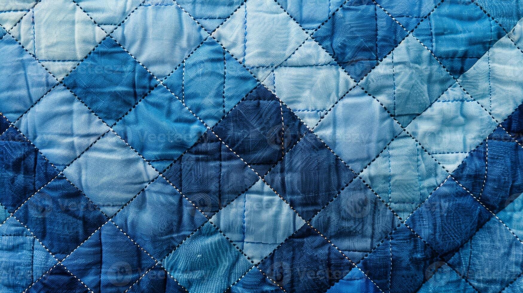 The textured fabric of a quilted blanket shows a repeating pattern of quilted diamonds in various shades of blue photo