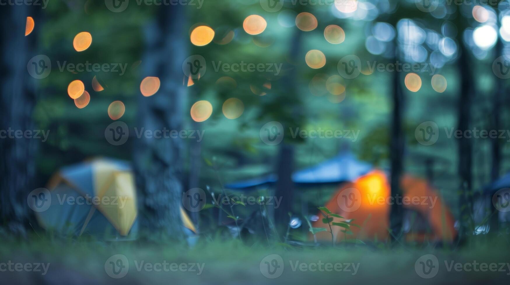 Blurry image of a campsite with soft shapes of tents and a faint firelight peeking through the trees photo