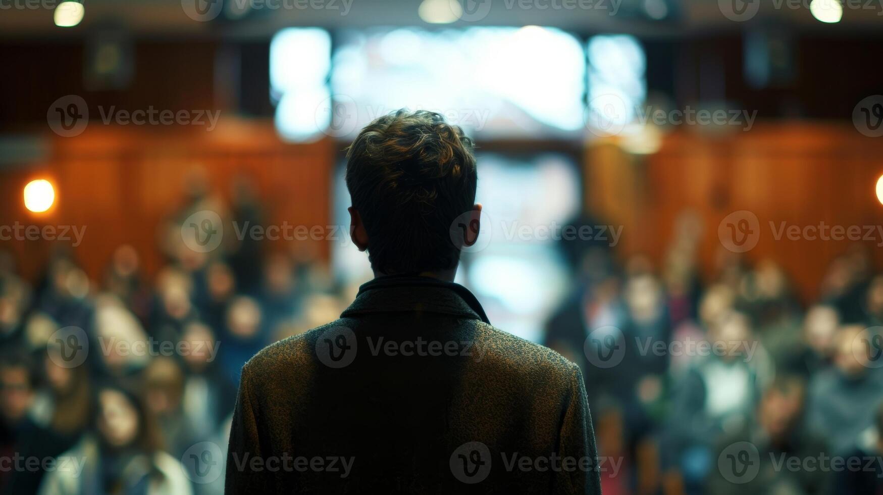 Blurred images of a lecturer and a crowded room at a thoughtprovoking public lecture photo