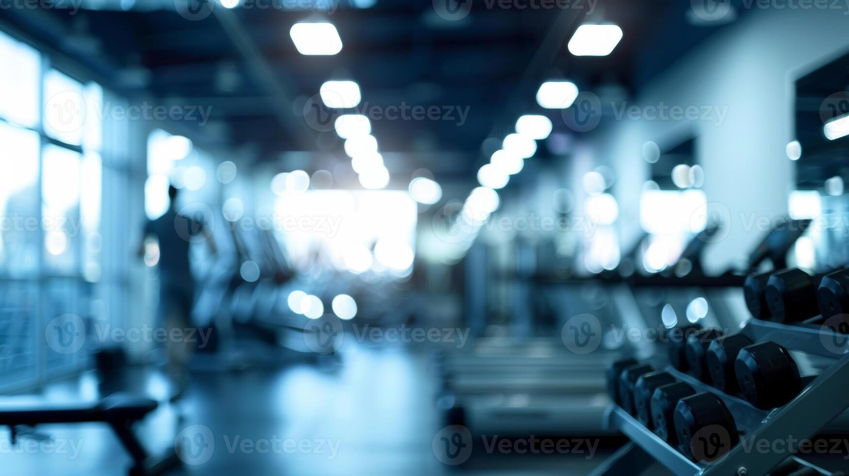 Defocused image of a bustling gym with silhouettes of figures working out in the background photo