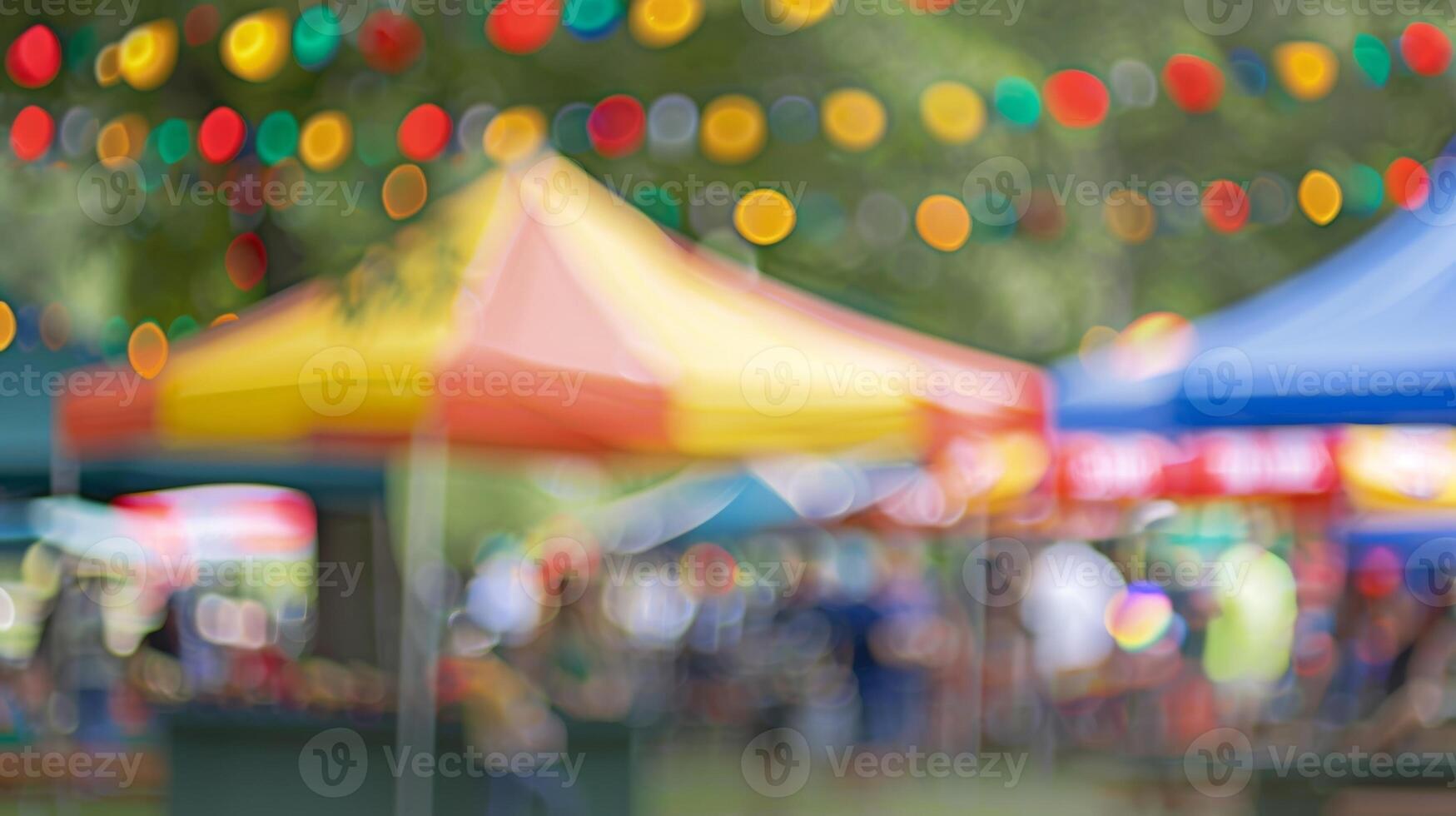 A blurred backdrop of colorful tents and bustling activity at an outdoor cooking contest photo