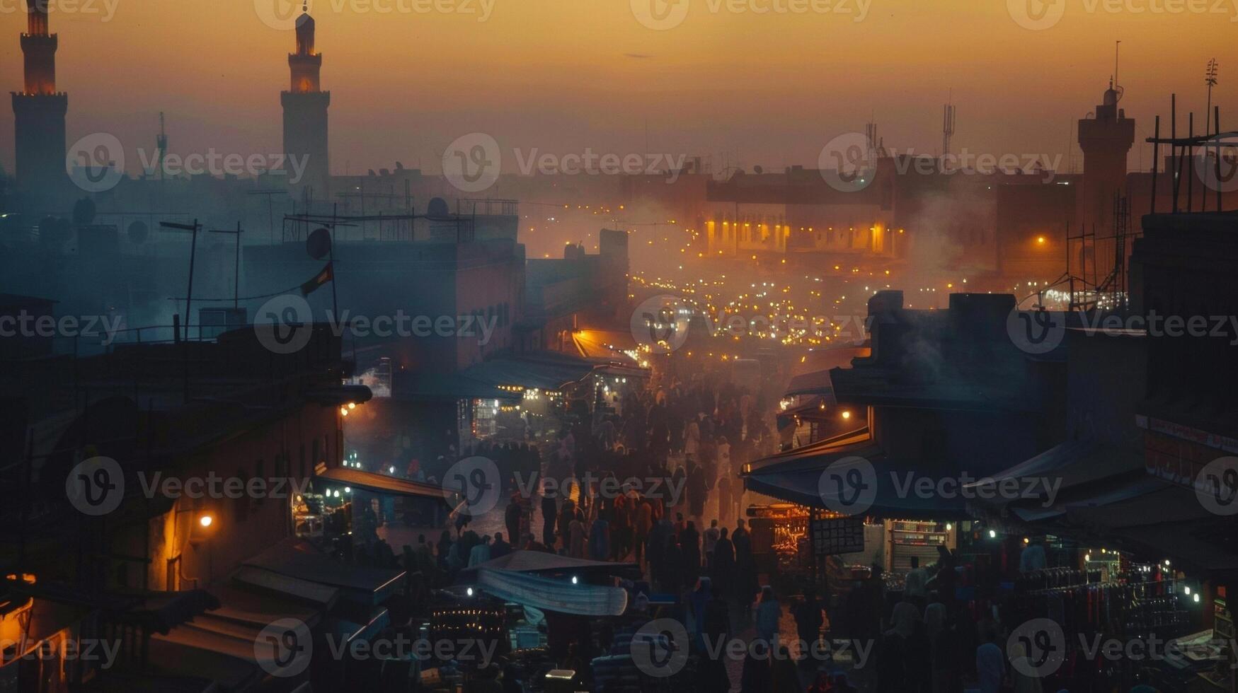 The hazy silhouette of buildings and structures framing a bustling market at dusk creating a magical backdrop for the vibrant chaos below. photo