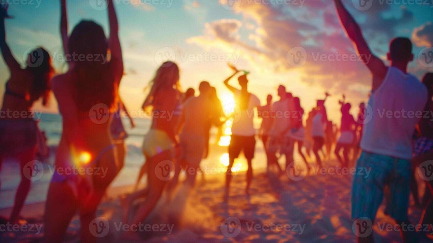 Defocused view of a beach party with groups of friends dancing and laughing together caught up in the victory vibes of the moment. photo