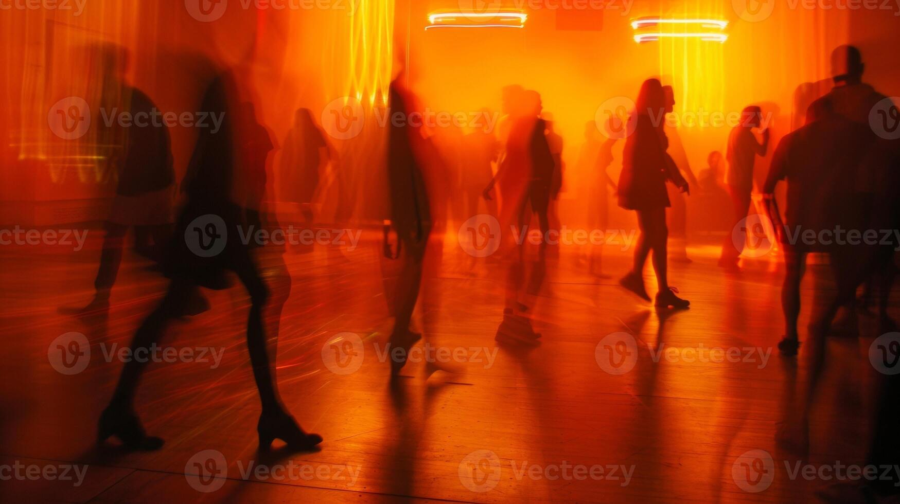 The dimly lit room is transformed by a dreamy blur of orange and yellow with the silhouettes of dancers twirling and raving in the background creating a mesmerizing atmosphere at photo