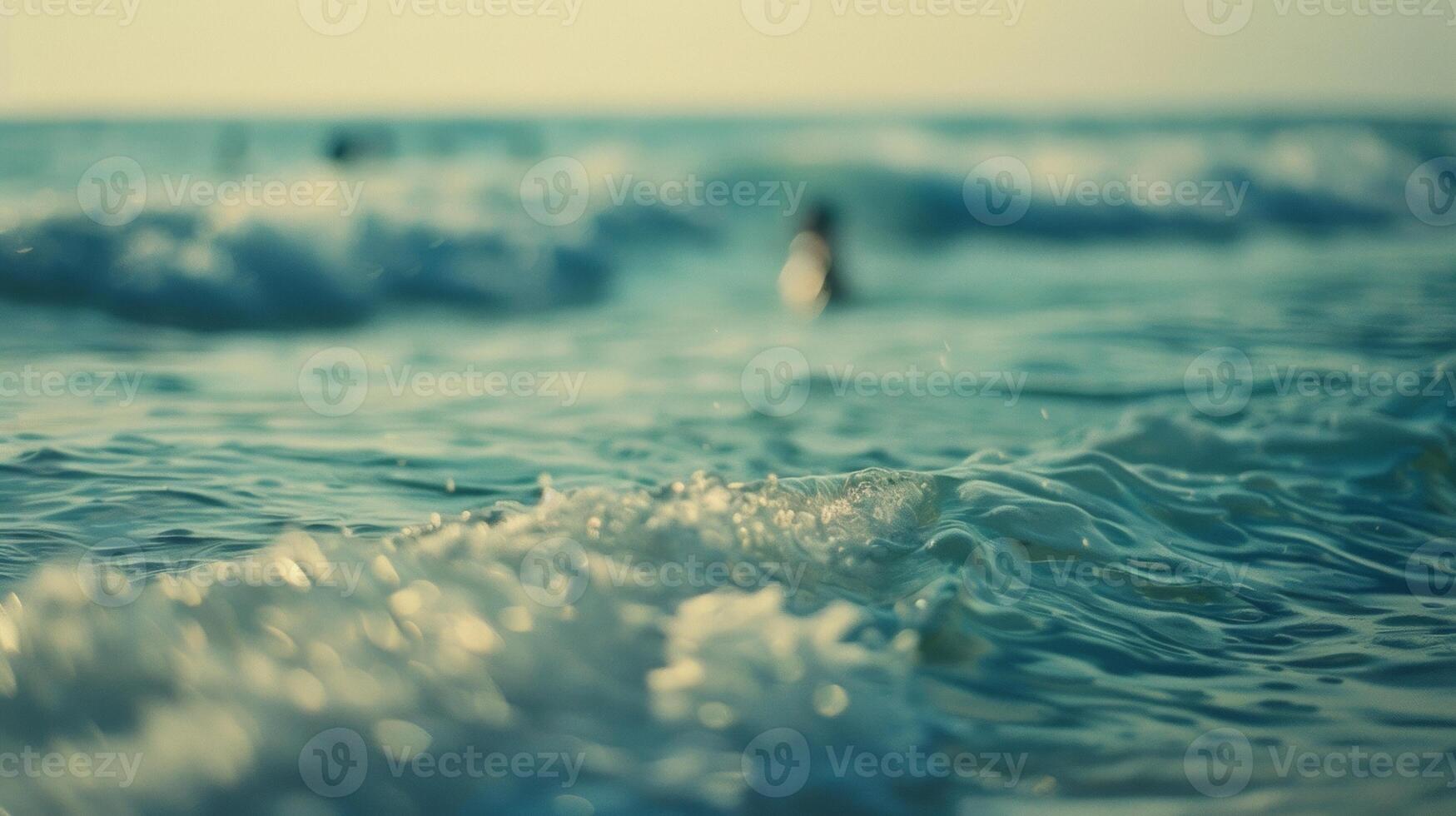 Defocused ocean shore Hazy swathes of blue and green blend together creating a blurred backdrop to the rhythmic waves that ebb and flow along the coastline. Small pops of color hint photo